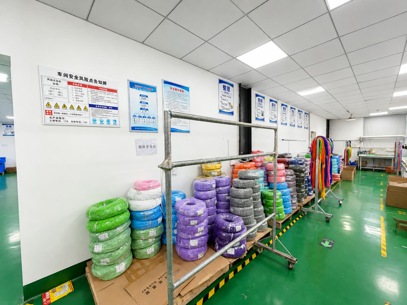 Workshop material area with coils of purple, green, blue, pink and black cable beside racks of prepared cable lengths